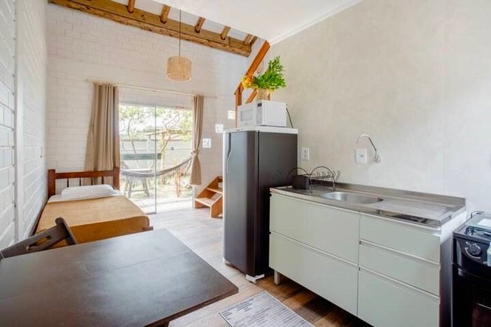 Térreo de um Loft, com cama de solteiro, cozinha e vista para a rede